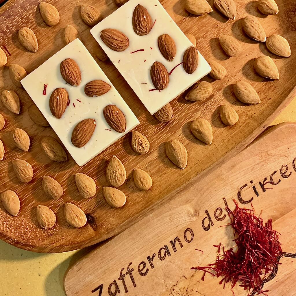 Cioccolato artigianale bianco con mandorle e zafferano panoramica su tagliere in legno